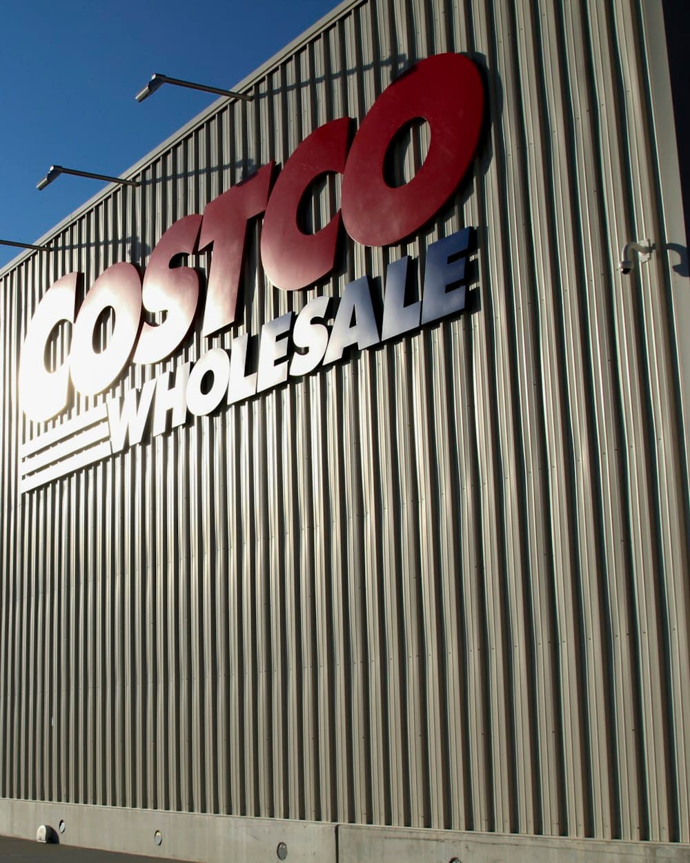 The Costco Wholesale sign across a warehouse wall against an evening sky