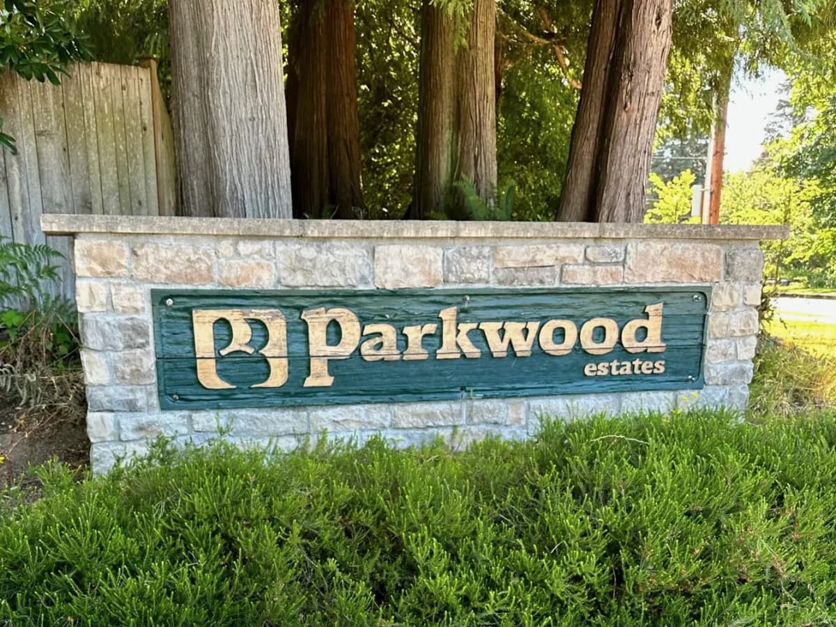 Parkwood Estates stone monument sign with gold lettering framed by western red cedars in Duvall WA